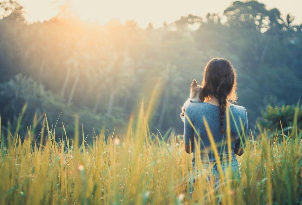 Woman holding a dog in a field